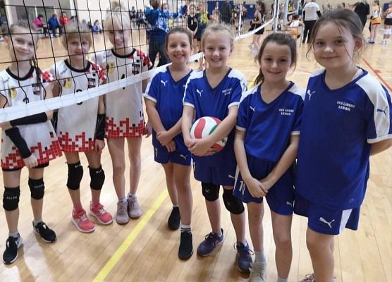 Dziewcznynki stoją na boisku do piłki siatkowej przed rozpoczęciem meczu