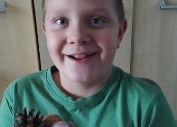 Uczeń pokazuje wykonany przez siebie jesienny stroik