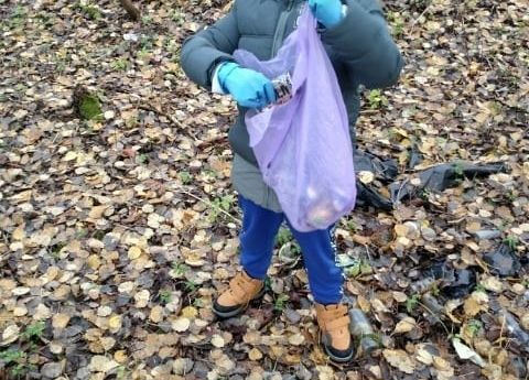 Uczeń zbiera śmieci podczas jesiennego spaceru