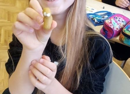 Uczennica prezentuje wykonanego z plasteliny rysia