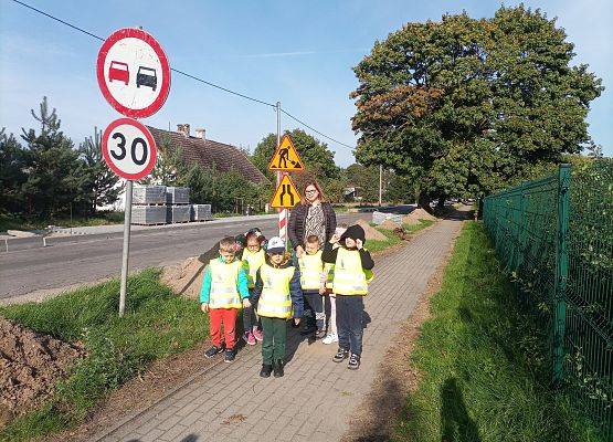 Dzieci wraz z nauczycielką na spacerze w poszukiwaniu znaków drogowych