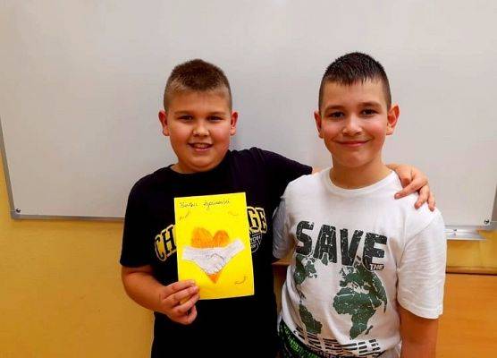 Dwaj uczniowie prezentuje kartkę z okazji Dnia Życzliwości i Pozdrowień