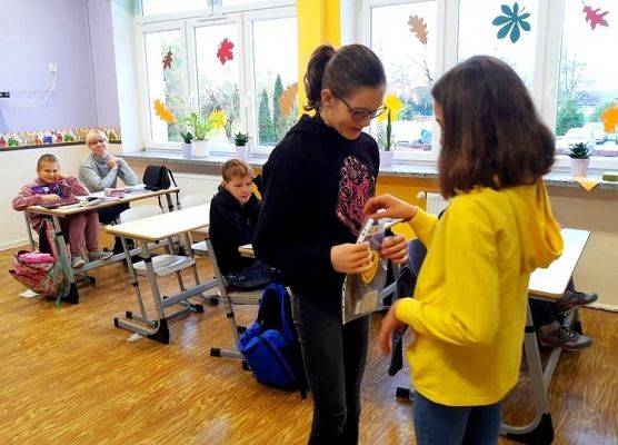 Wolontariuszka przekazuje kartki z życzeniami gospodarzowi klasy.
