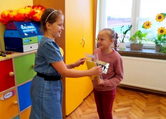 Wolontariuszka przekazuje kartki z życzeniami gospodarzowi klasy.