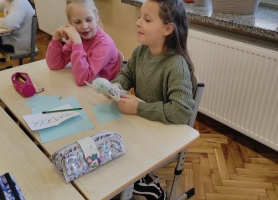 Uczennica siedząc przy stoliku opowiada o emocjach