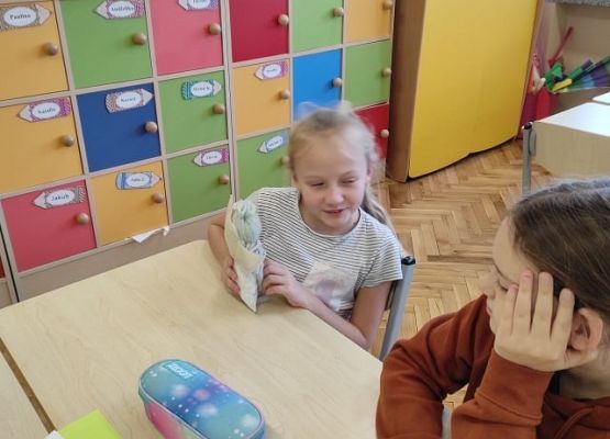 Uczennica siedząc przy stoliku opowiada o emocjach