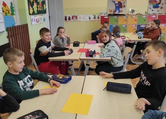 Uczniowie siedzą przy stolikach i pracując w grupach