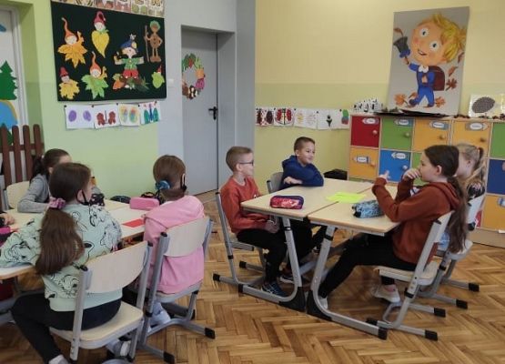 Uczniowie siedzą przy stolikach i pracując w grupach