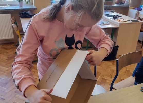 Uczennica okleja karton