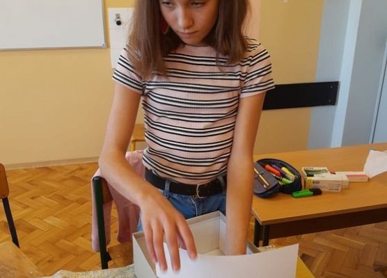 Uczennica wkłada do pudełka papier