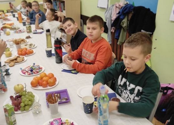 Dzieci siedzą przy stole podczas słodkiego poczęstunku