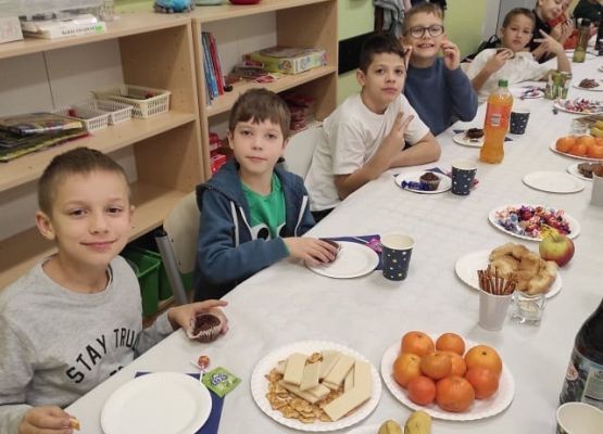 Dzieci siedzą przy stole podczas słodkiego poczęstunku