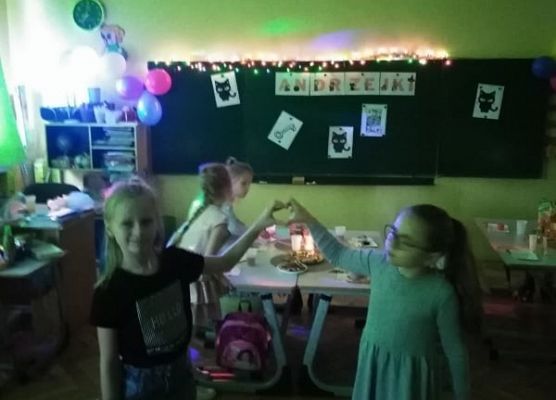 Dwie uczennice stoją i układają dłonie na kształt serca