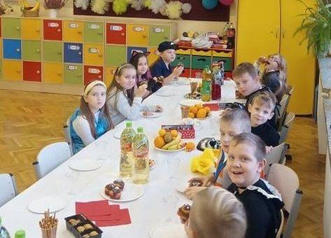 dzieci siedzą przy stole podczas słodkiego poczęstunku