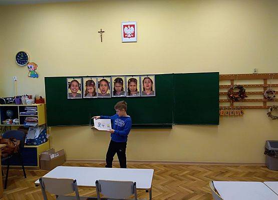 Uczeń stoi przy tablicy i  prezentuje swoją pracę