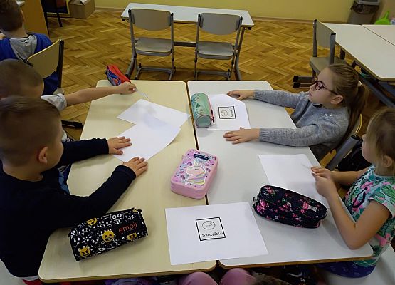 Uczniowie siedzą przy stoliku i pracują w grupie