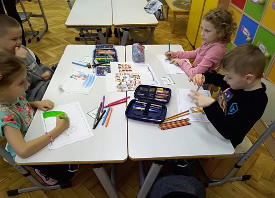 Uczniowie siedzą przy stoliku i pracują w grupie