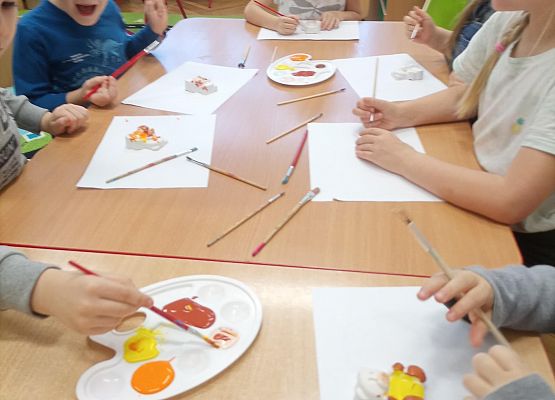 Dzieci siedzą przy stoliku i malują misie