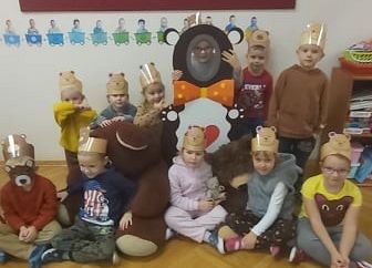 Zdjęcie grupowe siedzących dzieci przy ścianie