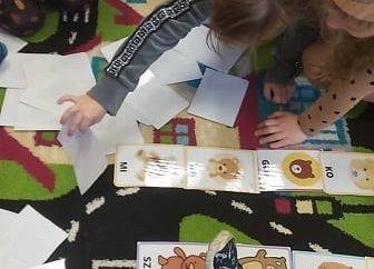 Dzieci na podłodze układają karty z misiami