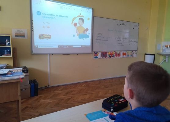 Uczeń siedzi w ławce i czyta ankietę