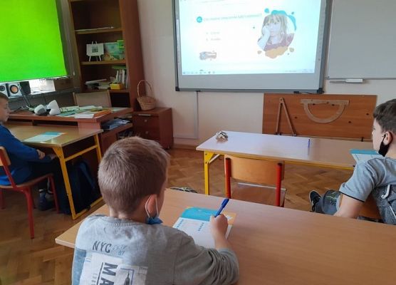 Uczeń siedzi w ławce i czyta ankietę