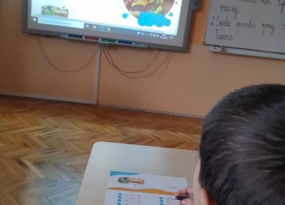 Uczeń siedzi w ławce i czyta ankietę