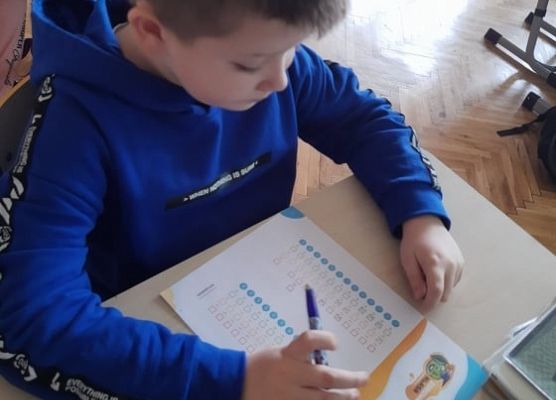 Uczeń siedzi w ławce i czyta ankietę