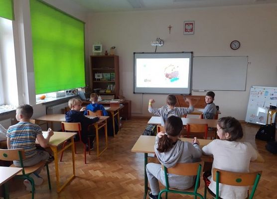 Uczniowie siedzą w ławkach i zapoznają się z ankietą