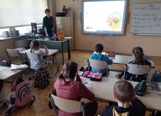 Uczniowie siedzą w ławkach i zapoznają się z ankietą