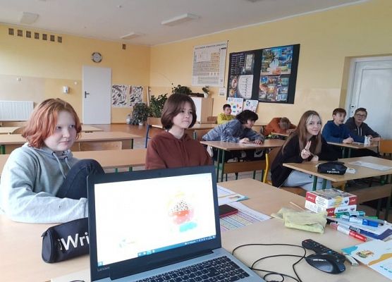 Uczniowie siedzą w ławkach i zapoznają się z ankietą