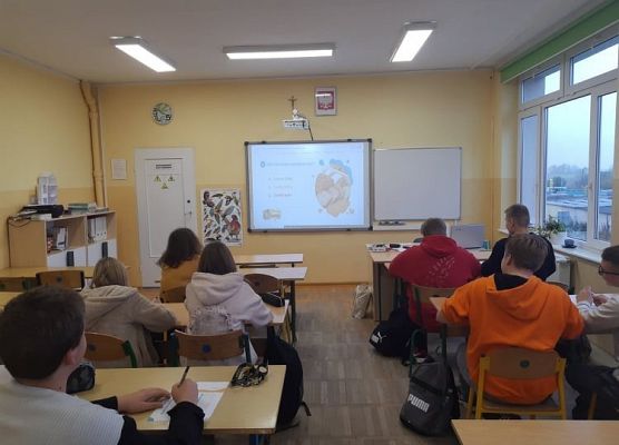 Uczniowie siedzą w ławkach i zapoznają się z ankietą