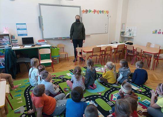 Gość ze Słowińskiego Parku Narodowego stoi i opowiada dzieciom. Dzieci siedzą na dywanie.