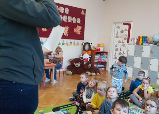 Gość ze Słowińskiego Parku Narodowego stoi i opowiada dzieciom. Dzieci siedzą na dywanie.