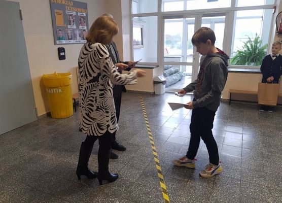 Pan Dyrektor i Pani Wicedyrektor wręczają uczniowi nagrodę