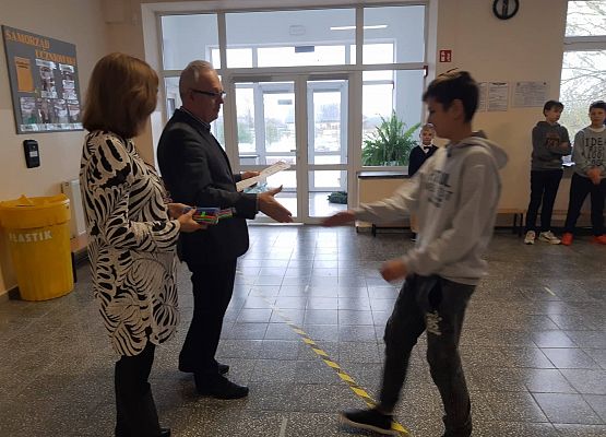 Pan Dyrektor i Pani Wicedyrektor wręczają uczniowi nagrodę