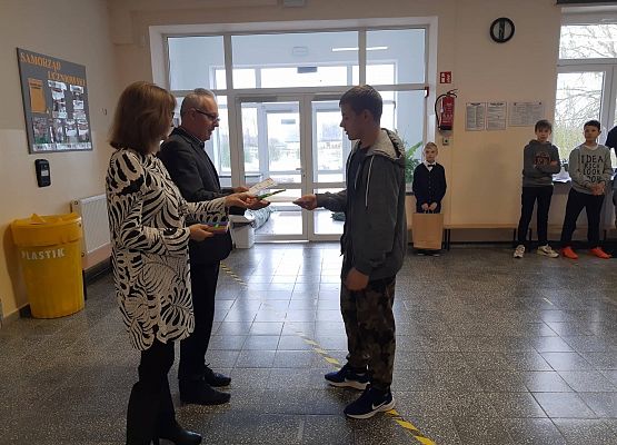 Pan Dyrektor i Pani Wicedyrektor wręczają uczniowi nagrodę
