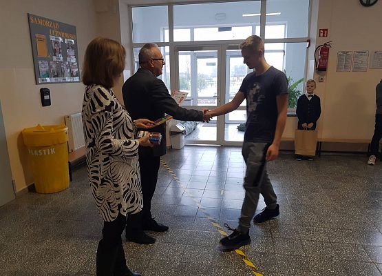 Pan Dyrektor i Pani Wicedyrektor wręczają uczniowi nagrodę