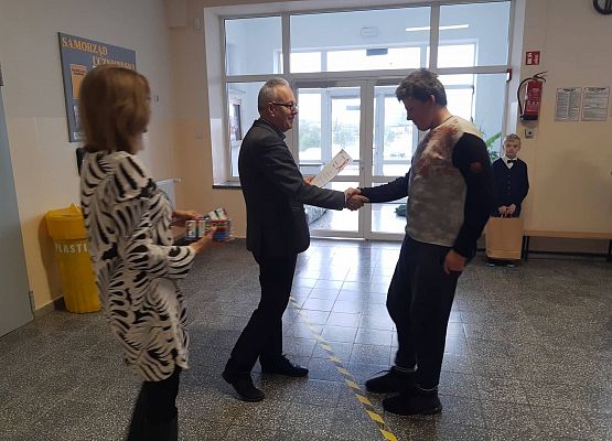 Pan Dyrektor i Pani Wicedyrektor wręczają uczniowi  nagrodę