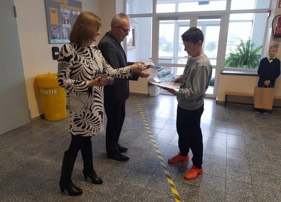Pan Dyrektor i Pani Wicedyrektor wręczają uczniowi  nagrodę
