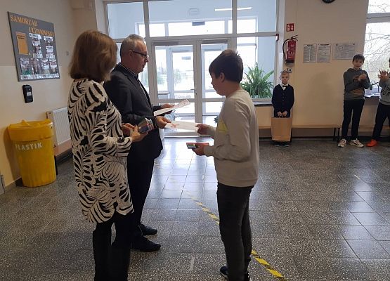 Pan Dyrektor i Pani Wicedyrektor wręczają uczniowi  nagrodę