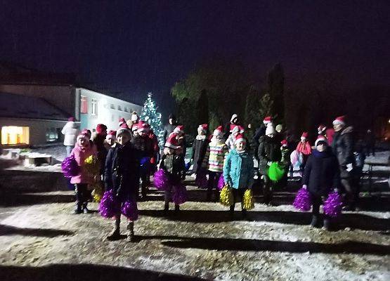 Grupa dzieci z kolorowymi pomponami tańczy na placu