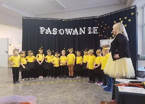 Dzieci przebrane za pszczółki stoją na tle dekoracji