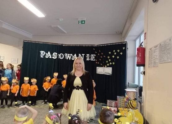 Nauczycielka stoi, za nią grupa przedszkolaków