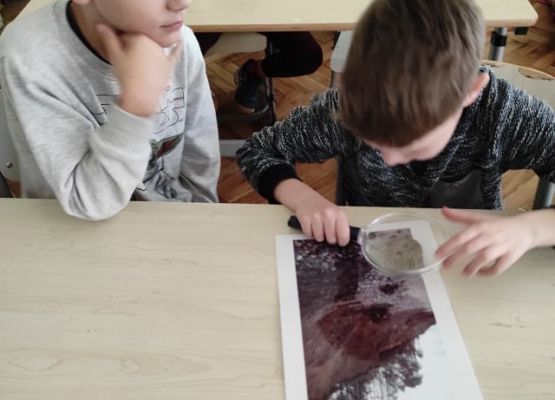 Uczeń patrzy przez lupę