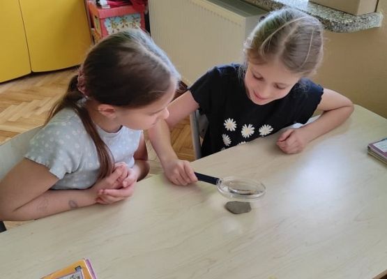 Uczennica patrzy przez lupę