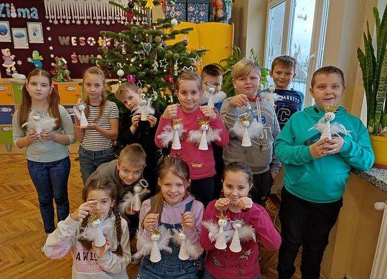 Uczniowie przy choince prezentują swoje aniołki