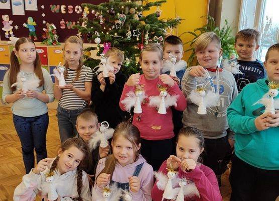 Uczniowie przy choince prezentują swoje aniołk