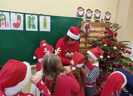 Nauczycielka z grupą uczniów. Wszyscy w mikołajkowych przebraniach.