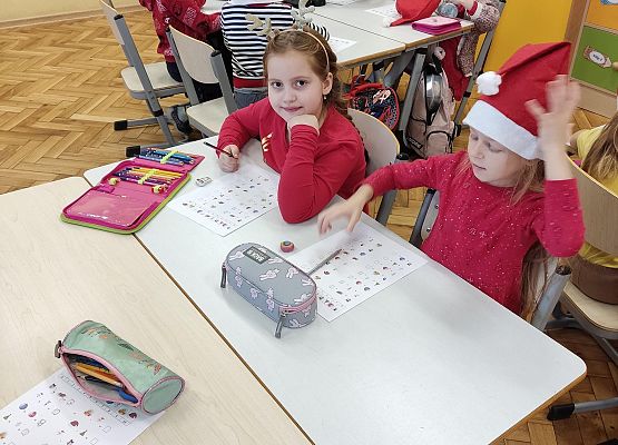 Dzieci w czerwonych, mikołajkowych ubraniach pracują przy stolikach